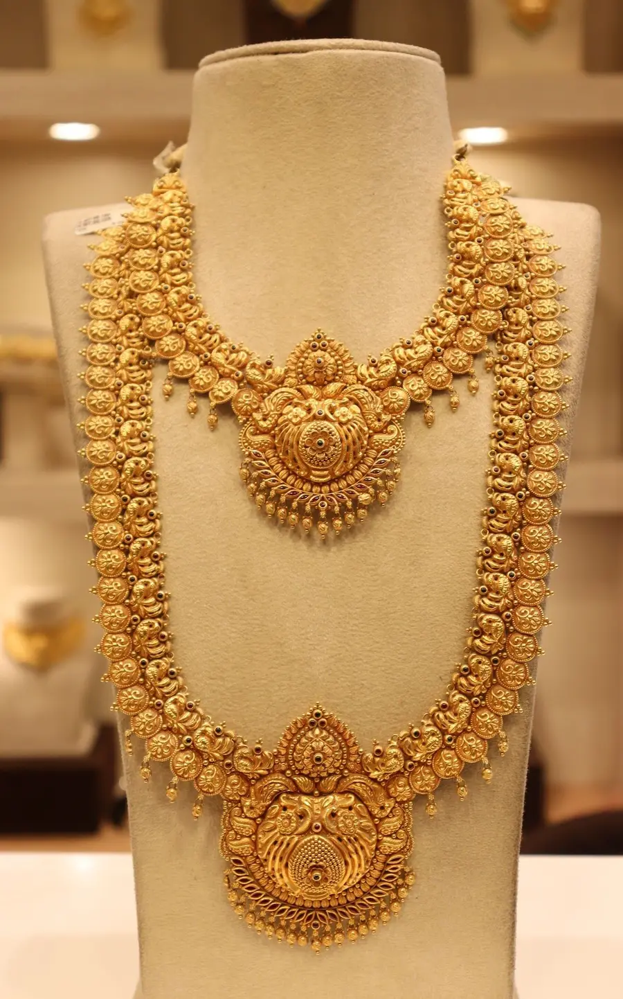 A two tier temple haram with a Lakshmi medallion on a cream bust.