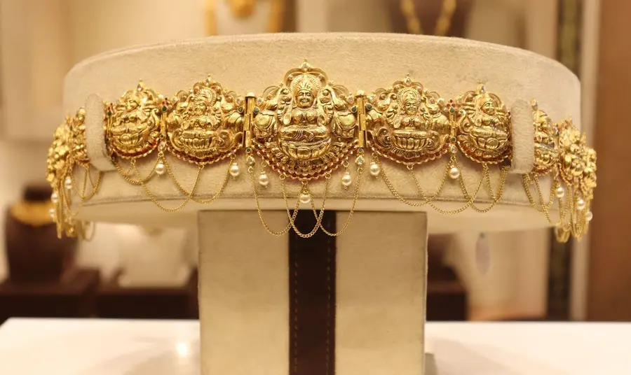 A gold vaddanam waist belt with Lakshmi medallions, displayed at full width.